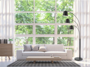 Lampe de plancher/perche moderne SENTADO Creation Nova CN4262 dans un salon près d'un divan blanc devant la fenêtre avec vue sur les arbres