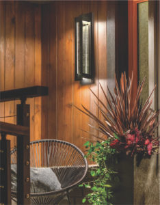 Wall Sconce Lighting outdoor RIVER PATH 49945BKTLED lit on a wall of wood with a chair and plants