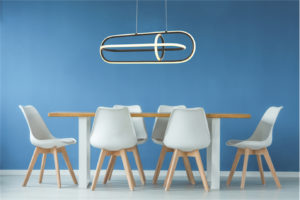 Luminaire suspendu HALO LL1795 au-dessus de la table de salle à manger en bois avec chaises blanches et mur bleu