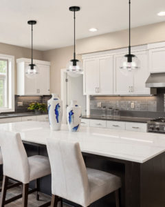 Luminaire suspendu moderne NEO Canarm IPL1051A01BK dans la cuisine au-dessus de l'ilôt blanc avec chaises confortables et armoires blanches